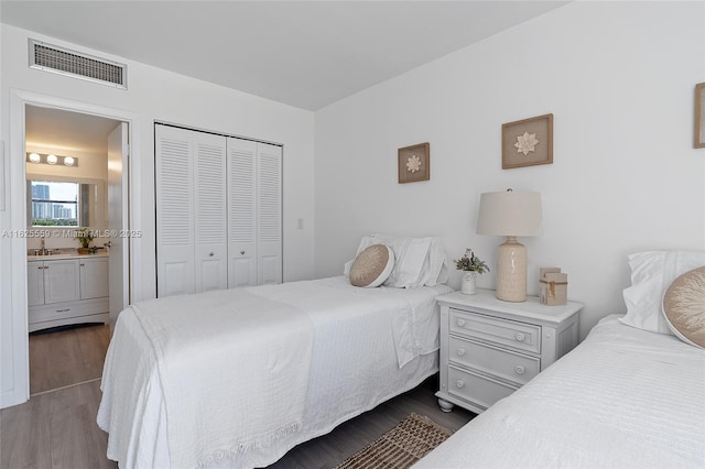 bedroom with sink, hardwood / wood-style flooring, a closet, and ensuite bathroom