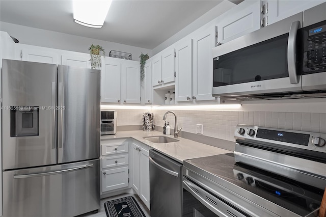 kitchen featuring stainless steel appliances, sink, white cabinets, and backsplash