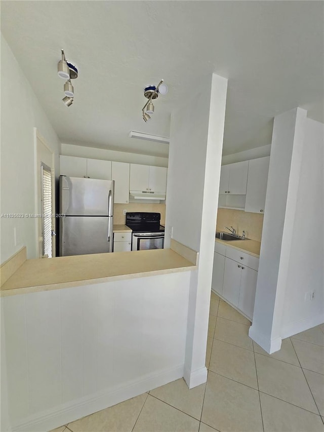 kitchen with electric stove, stainless steel fridge, sink, light tile patterned floors, and white cabinetry