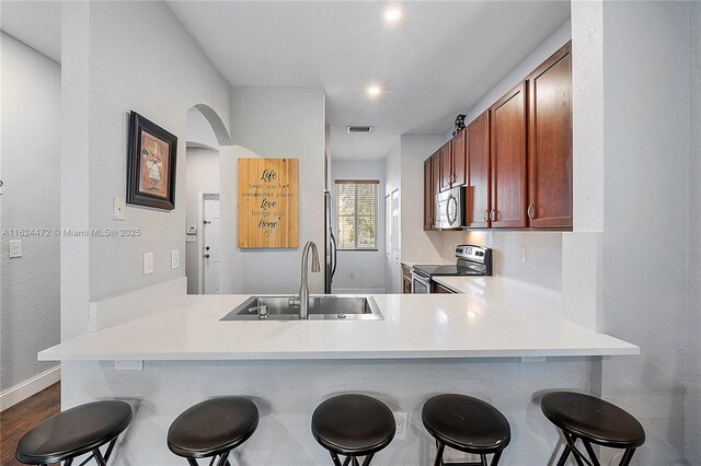 kitchen with a kitchen breakfast bar, kitchen peninsula, sink, and stainless steel appliances