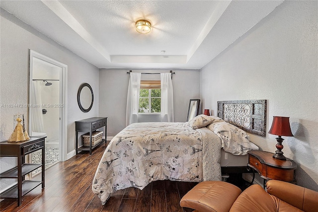 bedroom with a textured ceiling, a tray ceiling, and dark hardwood / wood-style floors