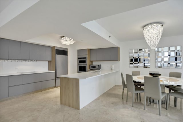 kitchen with an inviting chandelier, appliances with stainless steel finishes, gray cabinetry, and light tile patterned floors