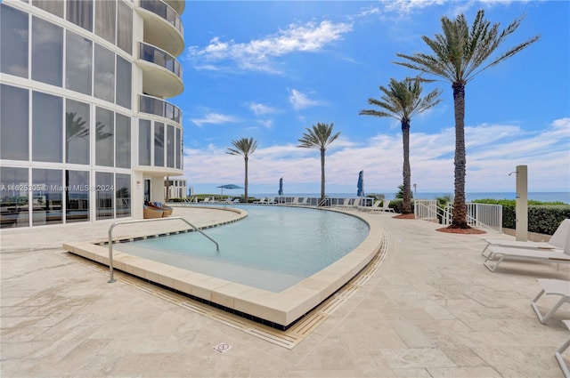 view of swimming pool with a water view and a patio