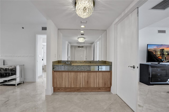 bathroom with an inviting chandelier, vanity, and tile patterned floors