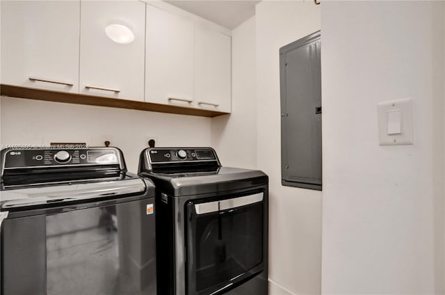 clothes washing area featuring electric panel, washing machine and dryer, and cabinets