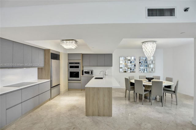 kitchen with appliances with stainless steel finishes, a chandelier, light tile patterned flooring, and gray cabinets