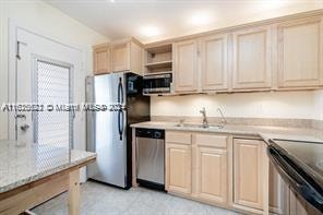 kitchen featuring appliances with stainless steel finishes, light tile patterned floors, sink, and light brown cabinets