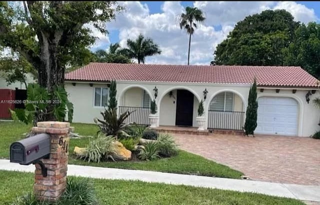 mediterranean / spanish house with covered porch and a garage