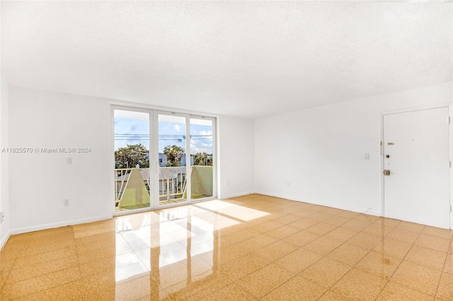 tiled spare room with a textured ceiling and floor to ceiling windows