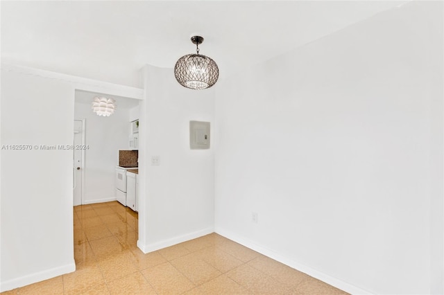 spare room featuring light floors, electric panel, baseboards, and a chandelier