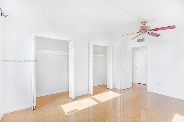 unfurnished bedroom with multiple closets, tile patterned flooring, and ceiling fan