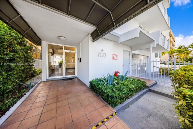 doorway to property featuring fence and stucco siding
