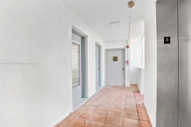 hallway with elevator and light tile patterned floors