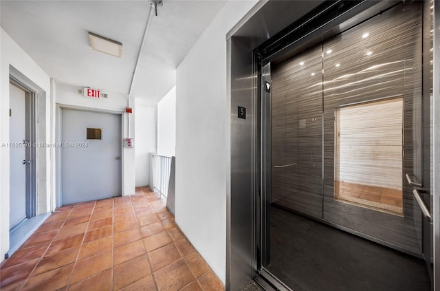 corridor featuring elevator and light tile patterned flooring