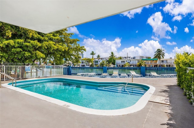 pool with a patio area and fence