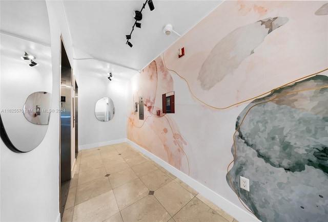 hall with baseboards, light tile patterned flooring, and electric panel