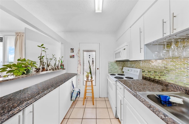 kitchen with tasteful backsplash, dark stone counters, white appliances, white cabinets, and light tile patterned floors