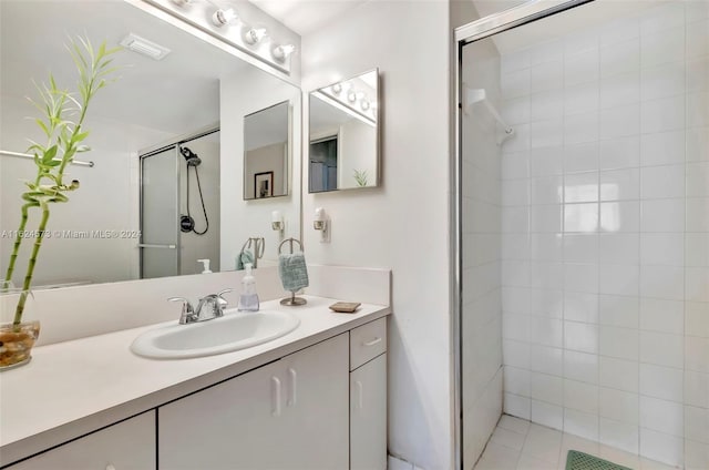 bathroom featuring a shower with shower door, vanity, and tile patterned floors