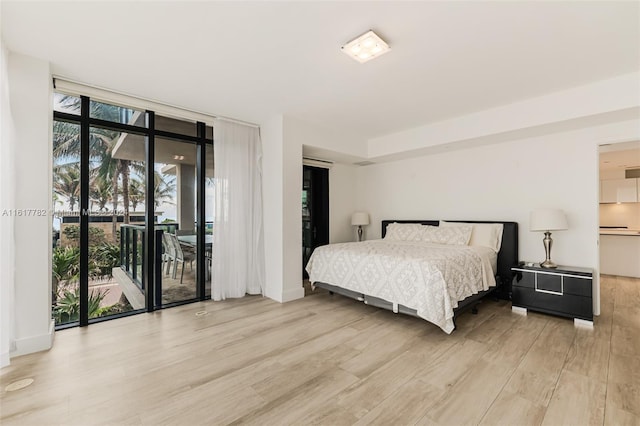 bedroom featuring access to outside, a wall of windows, and light hardwood / wood-style flooring