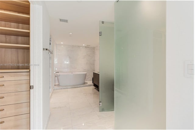 bathroom featuring tile patterned floors, tile walls, a tub to relax in, and vanity