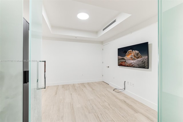 spare room with light hardwood / wood-style floors and a raised ceiling