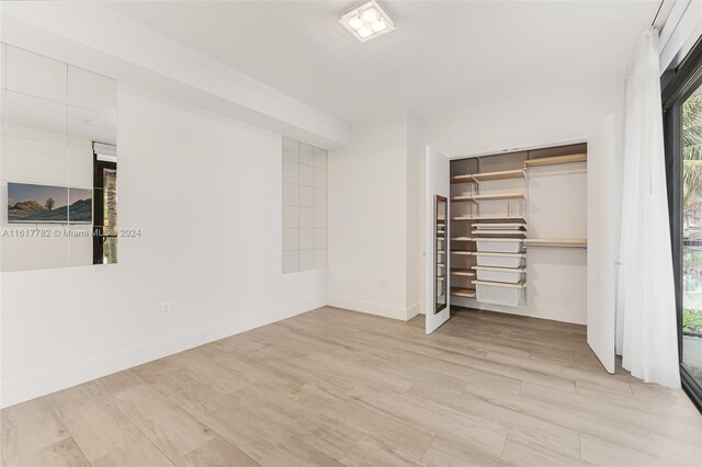 unfurnished bedroom with light wood-type flooring and a closet