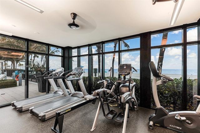 gym featuring ceiling fan, a wall of windows, and a water view