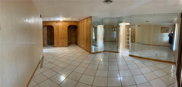 empty room featuring wooden walls and light tile patterned floors