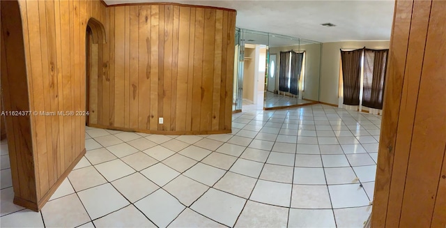 empty room featuring light tile patterned flooring and wood walls