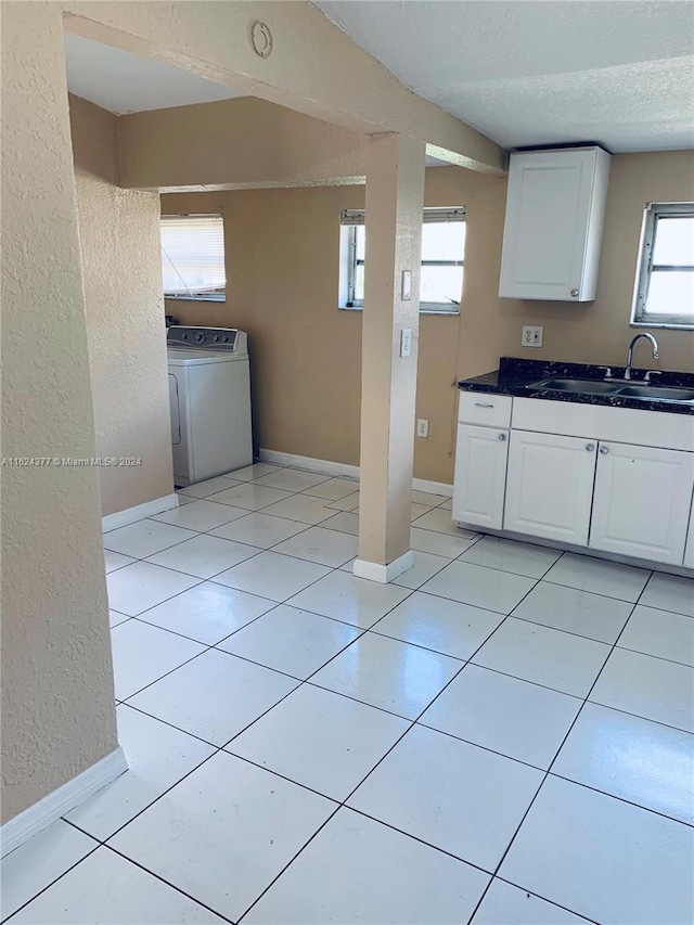 kitchen featuring washer / dryer, sink, a textured ceiling, light tile patterned floors, and white cabinets