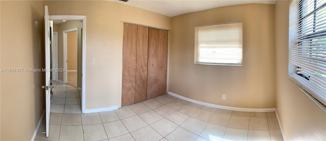 unfurnished bedroom with a closet, multiple windows, and light tile patterned floors