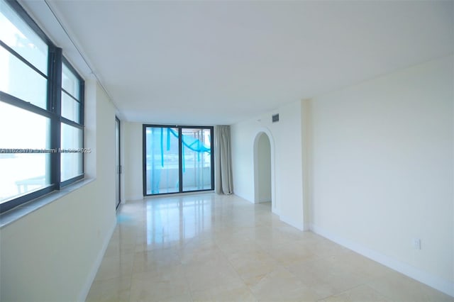 unfurnished room with floor to ceiling windows and a healthy amount of sunlight