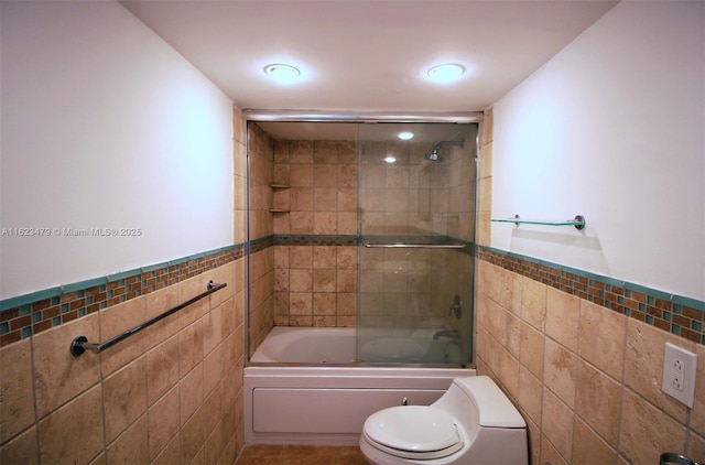 bathroom featuring shower / bath combination with glass door, tile walls, and toilet