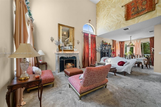 carpeted living room with a fireplace, a chandelier, and a high ceiling