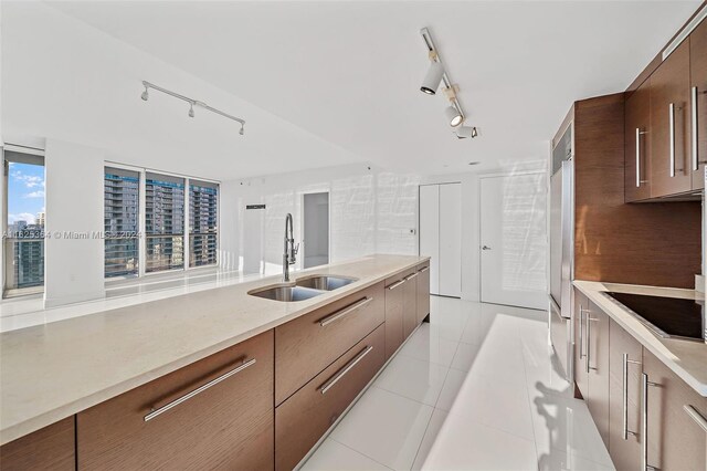 kitchen with sink, light tile patterned flooring, black electric cooktop, and rail lighting