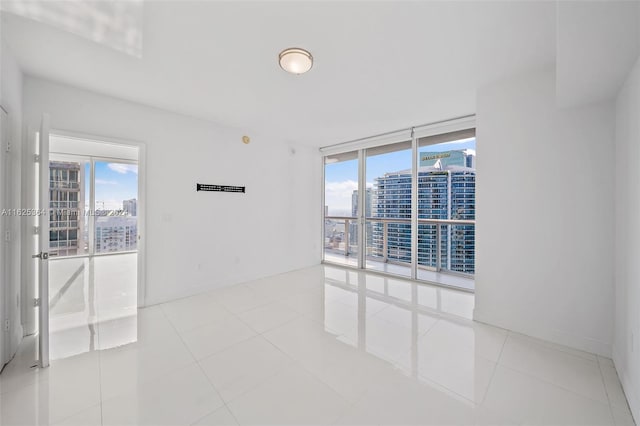 spare room featuring floor to ceiling windows and light tile patterned floors