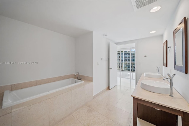 bathroom with tile patterned floors, vanity, and tiled bath