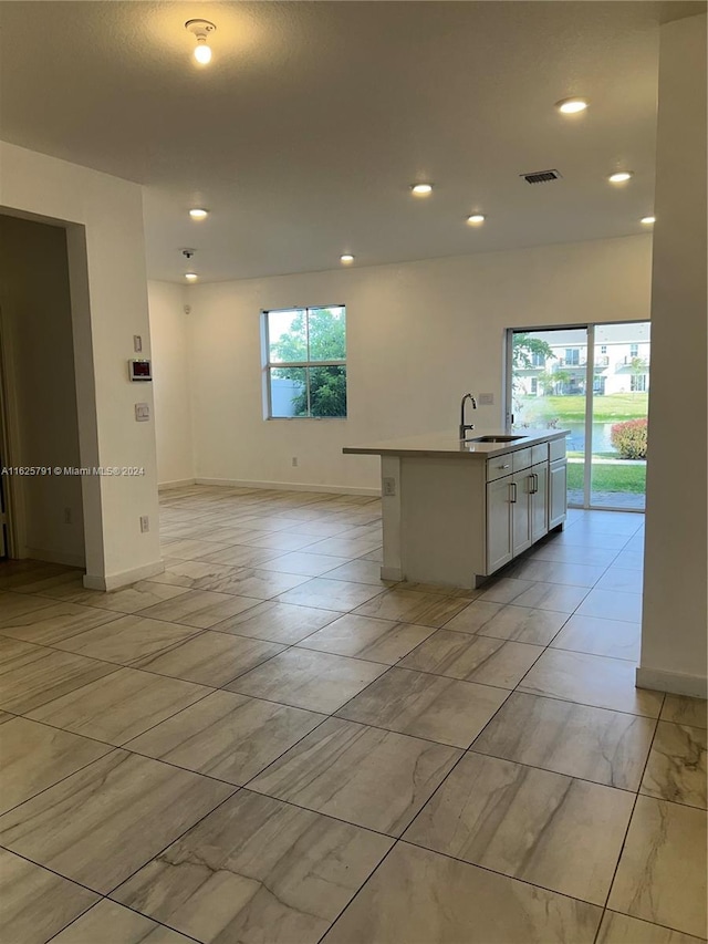 kitchen featuring a center island with sink, white cabinetry, and sink