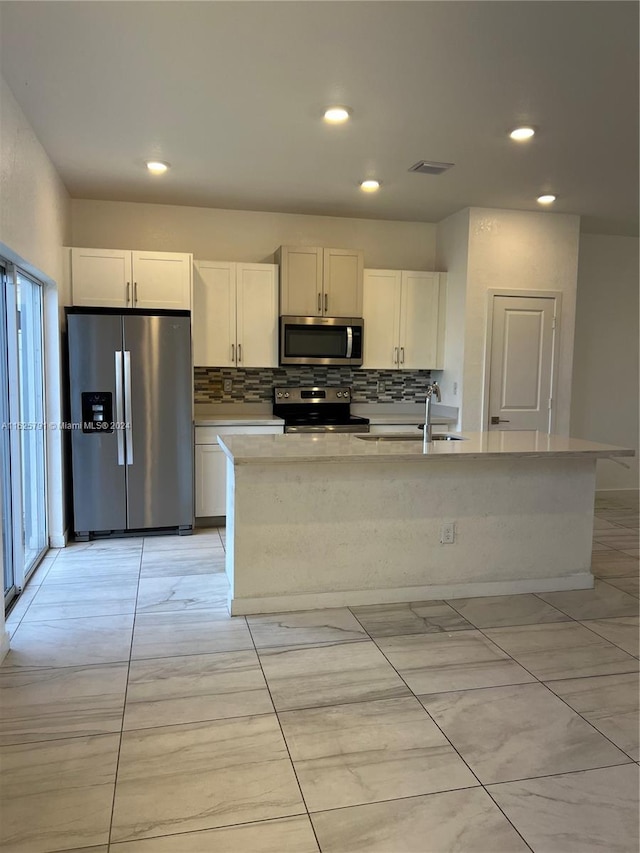 kitchen with white cabinets, sink, decorative backsplash, an island with sink, and appliances with stainless steel finishes