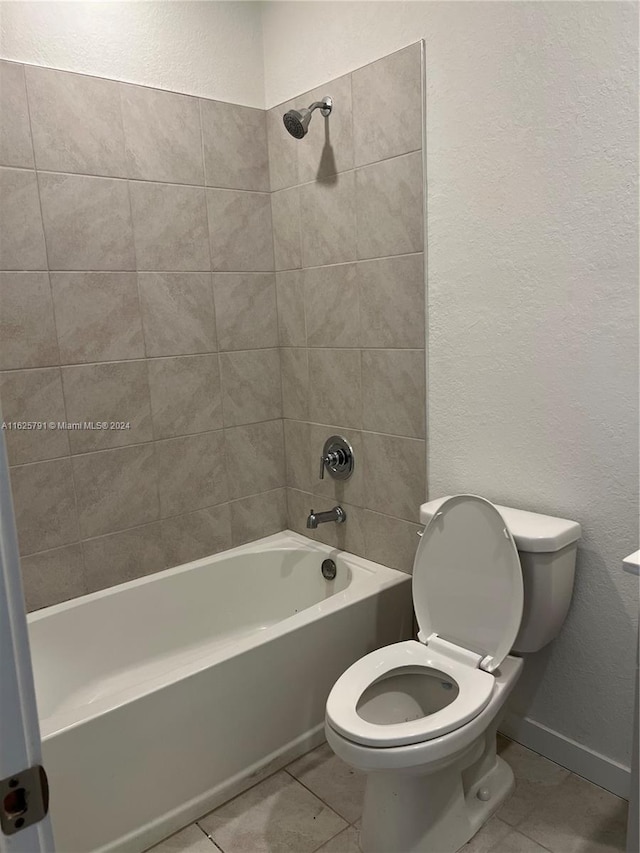 bathroom with tile patterned floors, tiled shower / bath combo, and toilet