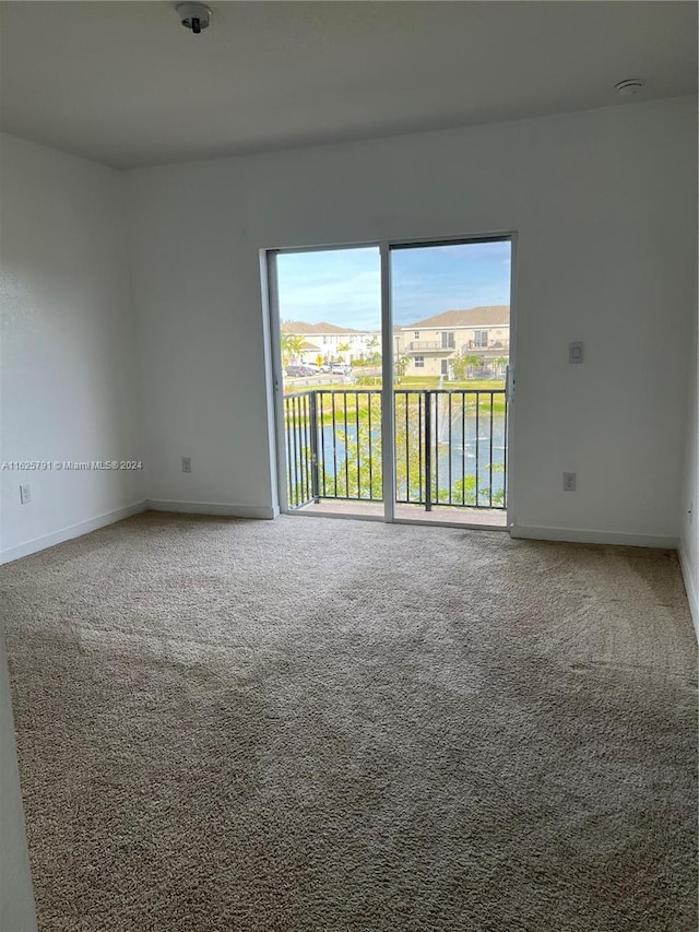 unfurnished room with carpet flooring and a water view