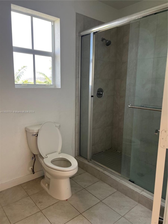 bathroom with tile patterned floors, a shower with door, and toilet