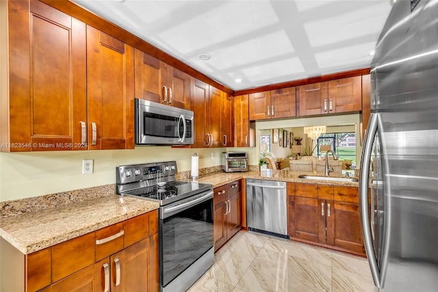 kitchen with appliances with stainless steel finishes, light stone counters, and sink