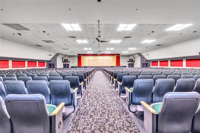 carpeted cinema featuring a drop ceiling