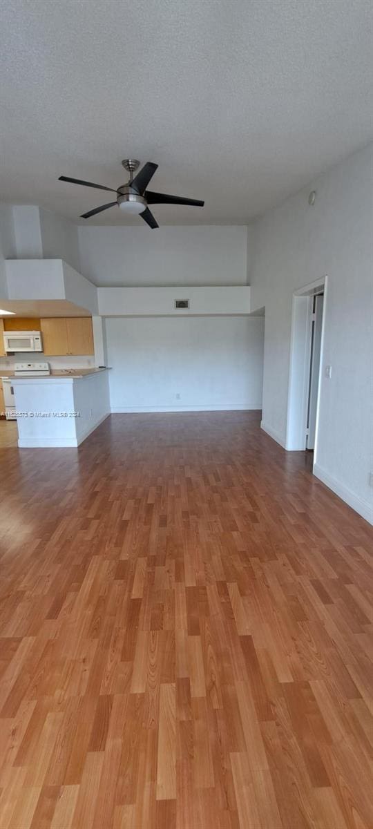 unfurnished living room featuring a textured ceiling, ceiling fan, and light hardwood / wood-style flooring