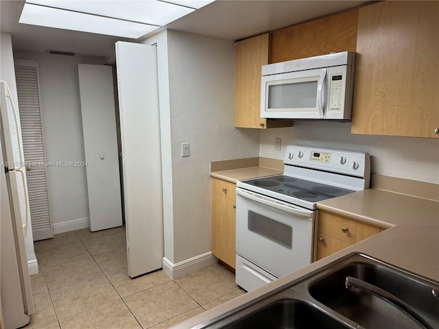 kitchen featuring light tile patterned flooring and white appliances