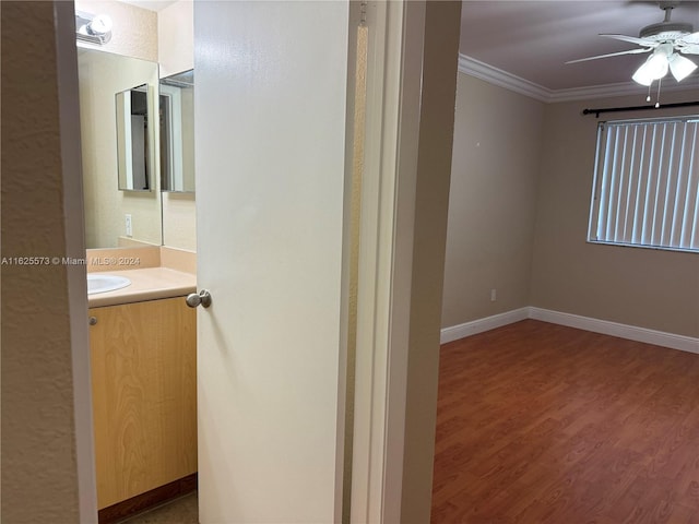 bathroom with ornamental molding, hardwood / wood-style flooring, ceiling fan, and vanity