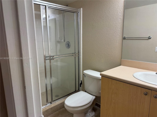 bathroom with a shower with door, vanity, and toilet