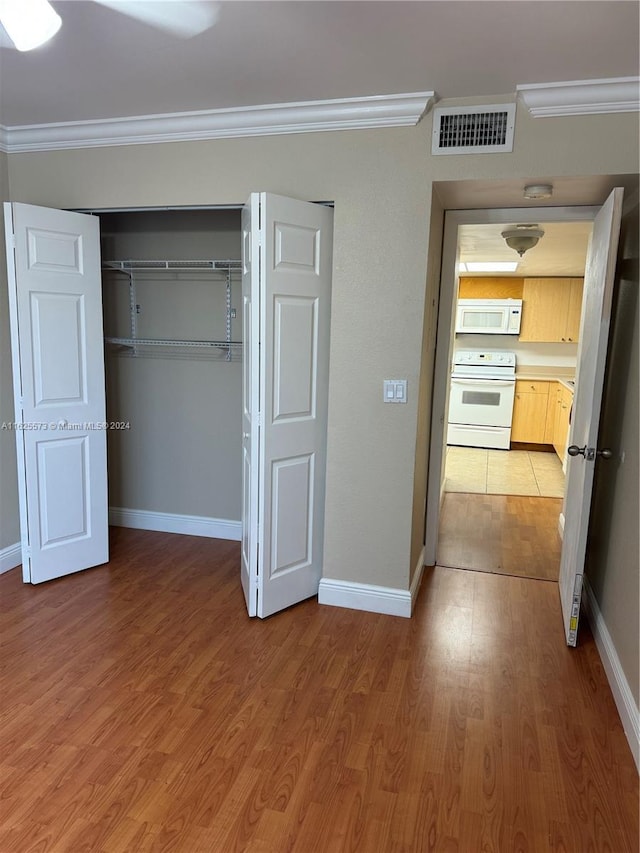 unfurnished bedroom featuring a closet, ornamental molding, and hardwood / wood-style floors