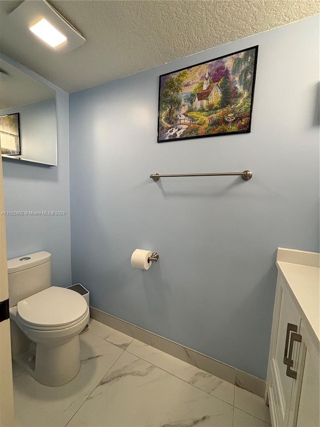 bathroom featuring vanity, toilet, and a textured ceiling